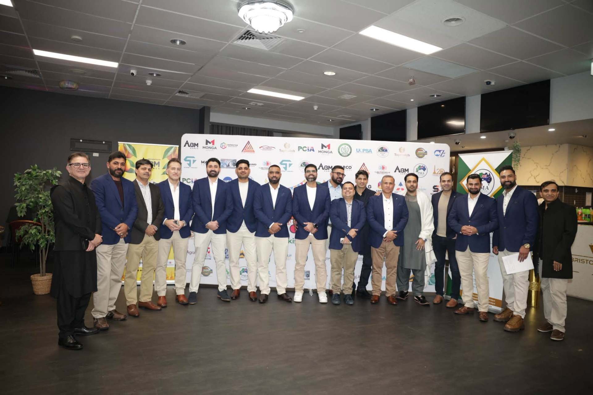 PMA committee gathered at the Mango Mela sponsor wall